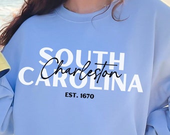 May include: A light blue sweatshirt with white text that reads "SOUTH Charleston CAROLINA EST. 1670".