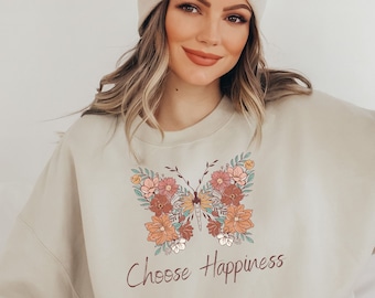 May include: A beige sweatshirt with a floral butterfly design and the text "Choose Happiness".