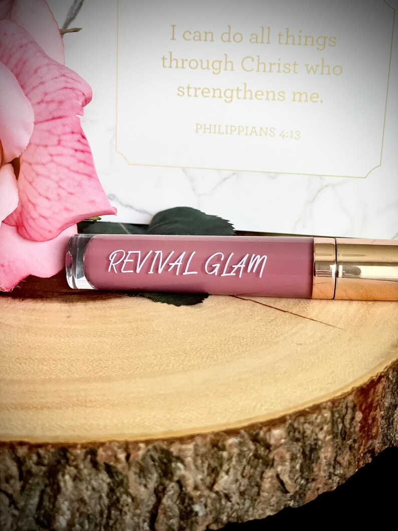 May include: A pink lip gloss tube with a gold cap. The tube has the words "REVIVAL GLAM" printed on it.