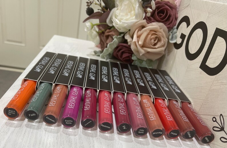 May include: A row of 12 small tubes of liquid lipstick in various shades of red, pink, orange, and brown. The tubes are labeled "Revival Glam" and "Matte Tinted".