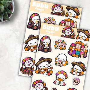May include: Two sticker sheets from Bubu Studio featuring cartoon characters celebrating Day of the Dead. The designs include figures in traditional attire, marigold flowers, sugar skulls, candles, and an altar with a framed portrait on a cream background.