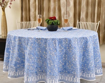May include: A blue and white floral round tablecloth with a white border. The tablecloth is laid on a round table with two chairs and a vase of flowers in the center.