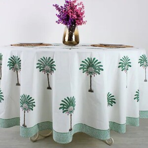 May include: White round tablecloth with a green palm tree print. The tablecloth has a green and white striped border.
