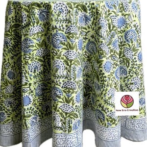 May include: A round tablecloth with a floral pattern. The tablecloth features a light green background with blue and white floral designs. The border has a striped pattern with a white floral design. The tablecloth is made of fabric.