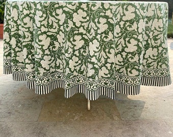 May include: A green and white floral patterned tablecloth with a black and white striped border. The tablecloth is draped over a round table.