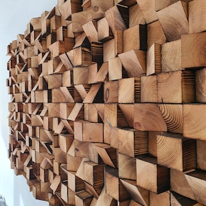 May include: A wall constructed from numerous wooden blocks, each varying in size and shape. The blocks are positioned in a random arrangement, resulting in a distinctive and visually appealing texture. The wood is a light brown hue, with subtle variations in shade across the blocks.