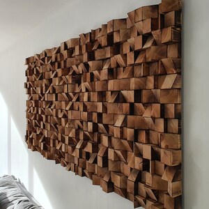 May include: A large wall art piece made of wood. The wood is arranged in a geometric pattern, creating a modern and abstract design. The wood is a dark brown color, and the piece has a rustic look.