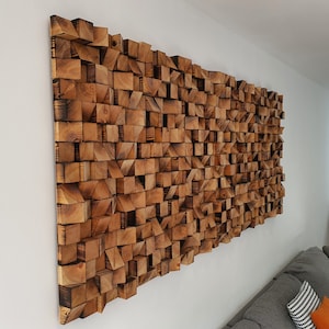 May include: A large wall art piece made of wood blocks in various sizes and shapes. The blocks are arranged in a random pattern and are stained a dark brown color.