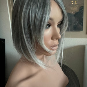 女性向けのバタフライバング付きティルスタイルのグレーヘアトッパー、ソルトアンドペッパーの淡いホワイトミックスヘア