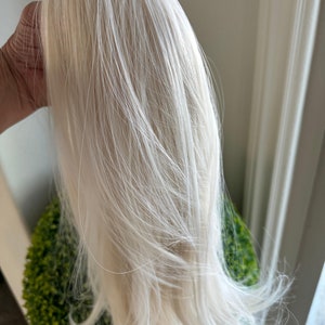 Op de afbeelding: Een lange, rechte, platinblonde haarverlenging. Het haar is erg licht en lijkt zijdezacht.