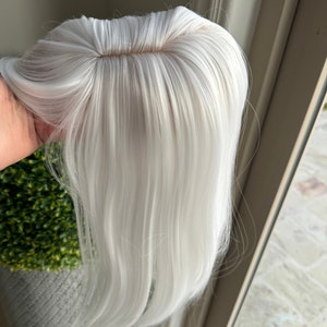 May include: A long, straight, white hair extension with a clip-in design. The hair is smooth and silky.