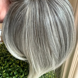 Aplique de cabelo grisalho com franja borboleta, em tons de branco claro.