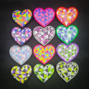 May include: Twelve heart-shaped patches with geometric patterns in various colors, including pink, red, green, purple, yellow, and blue. The patches are arranged in a grid pattern.