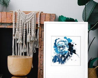 May include: A framed art print featuring a blue and black ink-splatter style portrait of a person with glasses and a bowtie. The artwork is presented in a white frame with a white mat, showcasing a high-contrast graphic illustration of a face.