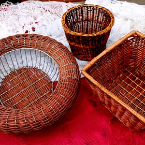 Peut inclure: Trois paniers en osier tressé de formes et de tailles différentes. Les paniers sont de couleur brune et ont une finition naturelle. Les paniers sont posés sur une nappe rouge.