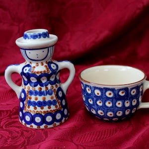 Könnte beinhalten: Eine blaue und weiße Keramik-Teetasse und eine blaue und weiße Keramikfigur einer Frau mit Hut. Die Figur trägt ein braunes und weißes gemustertes Kleid.