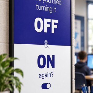 Op de afbeelding: Een rechthoekige wandposter in een zwarte lijst met een gespleten blauwe en witte achtergrond. De tekst luidt Have you tried turning it OFF & ON again? met een blauw tuimelschakelaar-icoon onderaan. Het ontwerp gebruikt dikke witte en blauwe letters.