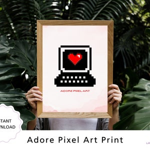 May include: A framed print of pixel art depicting a black computer with a red heart on the screen. The text "Adore Pixel Art" is below the image.
