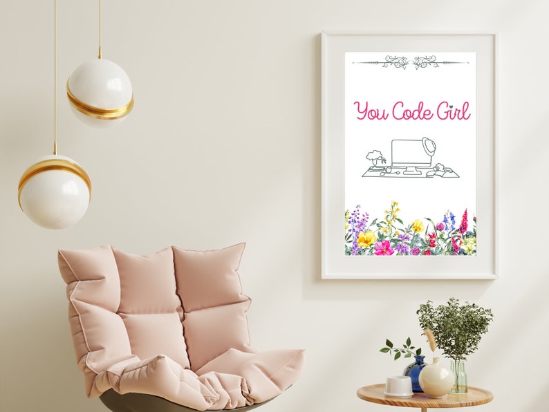 May include: A white framed print featuring a black and white line drawing of a computer desk with a laptop, a plant, and a hat on top of the laptop. The text "You Code Girl" is in pink lettering above the drawing. The bottom of the print has a border of watercolour flowers in various colours.