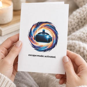 Puede incluir: Una tarjeta de felicitación blanca con una ilustración central de un casco de realidad virtual negro dentro de una galaxia arremolinada de tonos naranja, morado y azul. Debajo del gráfico, el texto dice: escape mode: activated.