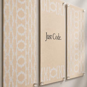 May include: Three rectangular wall art prints in a light beige color with a white repeating geometric pattern. The center print features the black text Just Code. Each print is secured to the wall with four small, clear, circular mounting pins.