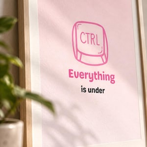 May include: A framed wall art print featuring a light pink background with a pink line-art illustration of a computer keyboard key labeled CTRL. Below the key, the text reads Everything in pink and is under in black, all encased in a light wood frame.
