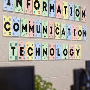 Op de afbeelding: Een wanddisplay met de woorden INFORMATION COMMUNICATION TECHNOLOGY gespeld op individuele rechthoekige kaarten. Elke kaart is pastelkleurig en versierd met kleine zwarte lijntekeningen gerelateerd aan digitale technologie.