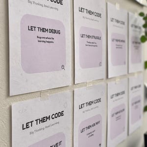 Könnte beinhalten: Eine Reihe weißer rechteckiger Poster mit schwarzem Text und hellvioletten abgerundeten Quadraten. Die Poster enthalten Sätze wie LET THEM CODE, LET THEM DEBUG, LET THEM STRUGGLE, LET THEM ASK WHY und LET THEM SOLVE IT sowie kleine Symbole.