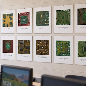 Pode incluir: Uma parede de galeria com dez impressões emolduradas apresentando fotografias em close-up de vários circuitos impressos verdes, castanhos e vermelhos. Cada impressão inclui uma borda branca e uma legenda manuscrita sob o componente.