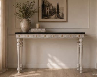 May include: A rectangular console table with a black top and a white base featuring fluted detailing, rope-style trim, and small gold-toned circular accents along the front edge. The table stands on four turned legs with a distressed white finish.