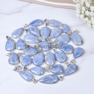 Puede incluir: Una colección de colgantes de cianita azul con engastes de metal plateado. Los colgantes tienen varias formas, incluyendo diseños de lágrima y ovalados. Las piedras de cianita tienen un aspecto veteado con tonos azules y blancos.