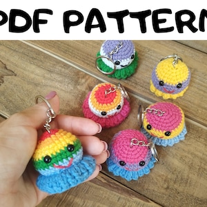 Puede incluir: Seis adornos de llavero de ganchillo con caras sonrientes. Los adornos son de varios colores, incluyendo morado, amarillo, rojo, rosa y arcoíris. Cada adorno tiene un llavero plateado.