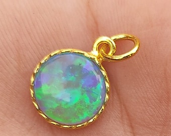 May include: A gold pendant with a round, green opal gemstone set in a gold bezel.
