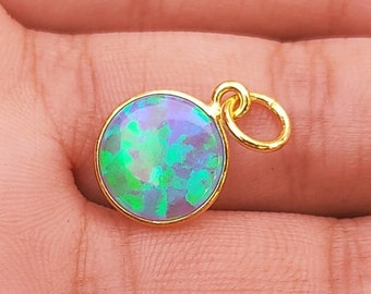 May include: A gold pendant with a round, iridescent opal gemstone. The opal has a green and blue color with a shimmery finish.