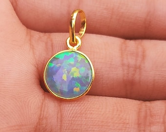 May include: A gold pendant with a round, iridescent opal gemstone. The opal has a blue, green, and yellow color.