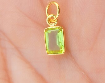 May include: A gold pendant featuring a light green rectangular gemstone.