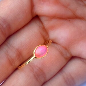 K&ouml;nnte beinhalten: Ein goldener Ring mit einem rosafarbenen ovalen Edelstein.
