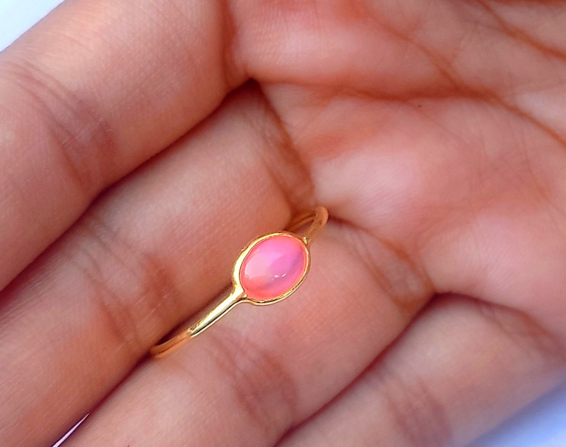 K&ouml;nnte beinhalten: Ein goldener Ring mit einem rosafarbenen ovalen Edelstein.