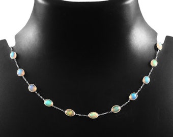 May include: A silver chain necklace with oval-shaped opal stones. The necklace has a delicate design and features a variety of opal colors, including white, blue, and green.