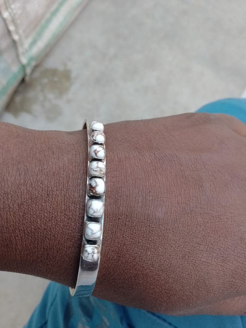May include: A silver bangle bracelet with white and brown marbled stones.