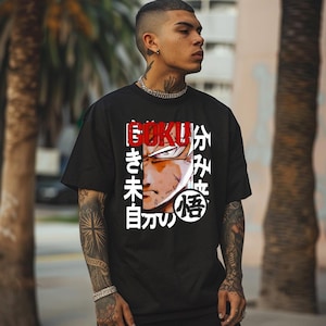 May include: Black t-shirt featuring a graphic of a character's face with the word "Goku" in red and Japanese text. The design is centered on the front of the shirt. The shirt has short sleeves and a crew neck.