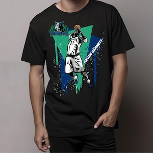 Pode incluir: Camiseta preta com um gráfico verde, azul e branco do jogador de basquete Kevin Garnett em ação. O gráfico inclui o texto "MINNESOTA TIMBERWOLVES" e "KEVIN GARNETT".