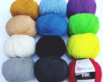 May include: Assortment of yarn balls in various colors, including yellow, blue, green, white, black, gray, and red. The yarn is labeled "YarnArt Jeans" and is 50 grams per ball.