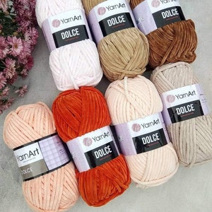 Puede incluir: Surtido de ovillos de lana en varios colores, incluyendo rosa, beige, marrón, naranja y melocotón. Cada ovillo tiene una etiqueta que dice "YarnArt Dolce".