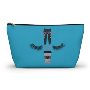 Könnte beinhalten: Eine türkisfarbene Reißverschlusstasche mit einem schwarzen Reißverschluss. Die Tasche hat ein grafisches Design mit einer schwarzen Leggings, einer Tasse Kaffee mit einem Herzen und Wimpern. Der Text "Leggings, Lashes, Latte" ist auf der Tasche aufgedruckt.