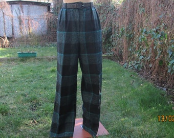 Peut inclure: Pantalon à jambes larges en tissu écossais noir et turquoise. Le pantalon a une ceinture avec passants et une ceinture noire avec une boucle argentée.