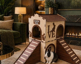 May include: A two-story wooden rabbit house with a brown roof and ramps. The house has arched openings and decorative rabbit cutouts. The word "LOVE" is visible on the side. A black and white rabbit sits near the house. The text "SEVENTEEN DESIGN" is on the front.