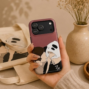 Op de afbeelding: Een donker mauve smartphonehoesje met een grafische illustratie van een persoon met bruin haar naast een persoon met een witte pandacapuchon. Het ontwerp bevat zwarte Chinese karakters in de rechterbenedenhoek en een zwarte camera-uitsparing.