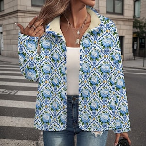 May include: A long-sleeved button-down jacket featuring a repeating pattern of blue and white floral vases with hydrangea bouquets. The jacket has a cream-colored interior lining, a fold-over collar, and a structured fit worn over a white top.