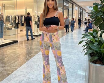 May include: A woman wearing a black crop top with a chain strap and floral print pants. The pants feature a patchwork design with yellow, purple, and pink flowers. She is standing in a shopping mall.